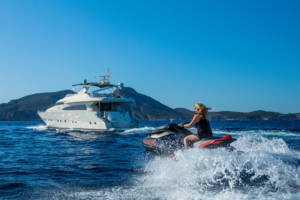 A woman on a jet ski speeding around the motor yacht